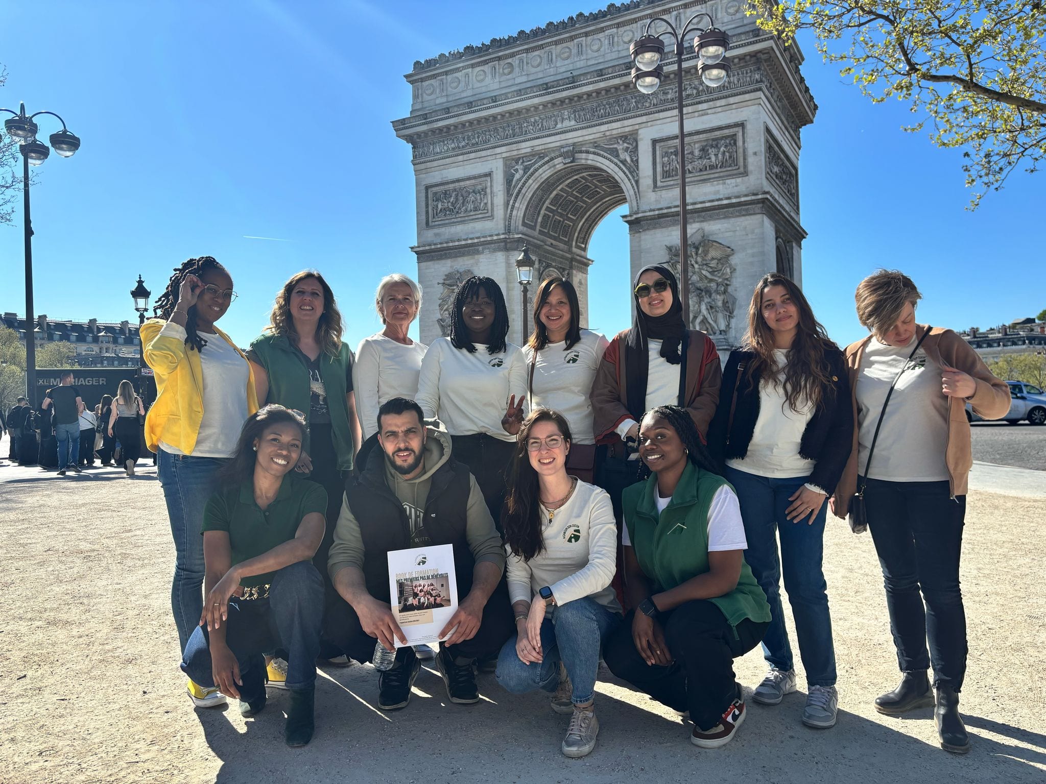 Douze bénévoles d’A Chacun Son Cocon, en t-shirts de l’association, réunis devant l’Arc de Triomphe à Paris